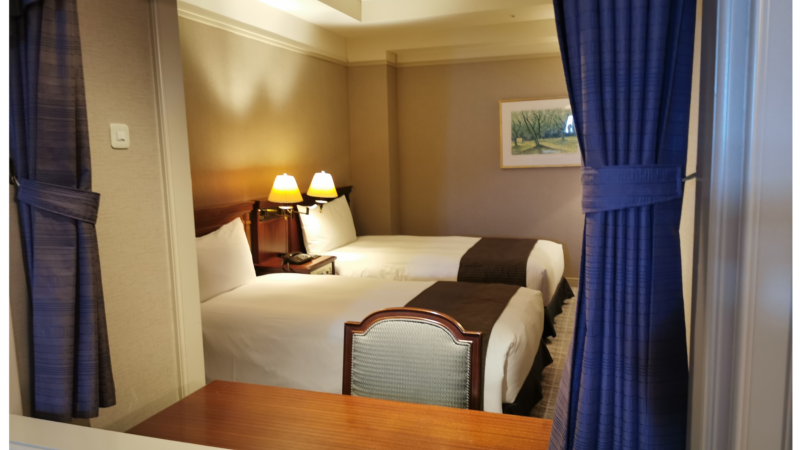 青いカーテンと、その向こうにベッドがある