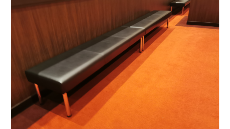 オレンジの床と黒い長椅子