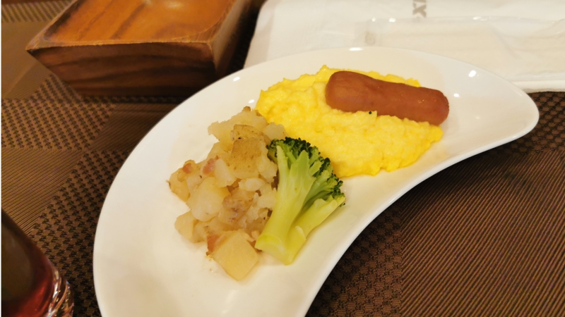 三日月形の皿に、ポテト、ブロッコリー、スクランブルエッグ、ソーセージ